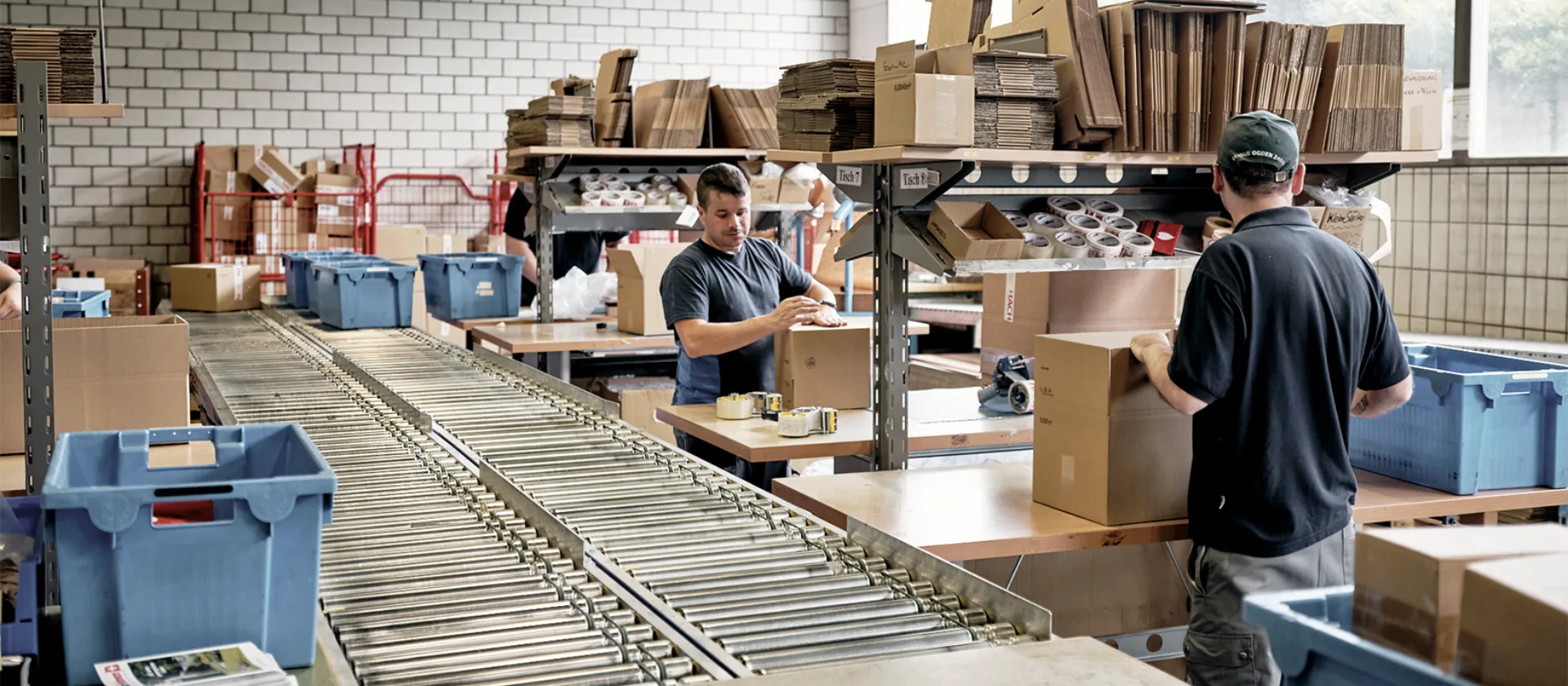 Das Foto zeigt die Halle mit Arbeitsstationen und dem Rollband in der Mitte.